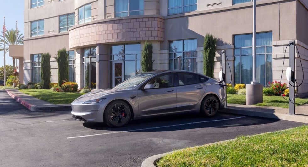 Silver Tesla parked at Tesla Wall Connectors in front of a hotel entrance